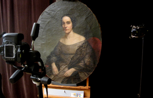 A large painting of a woman set up with a camera, lighting, and curtain for a photo shoot